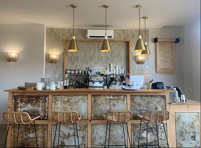 Modern kitchen with wooden counter, bar stools, and pendant lights.